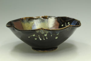 Ceramic bowl with black glaze and decorative patterns on a white background