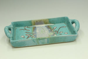 Turquoise ceramic tray with decorative patterns on a white background