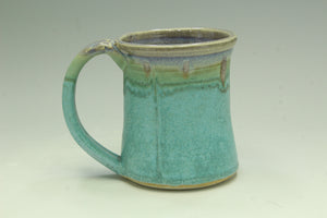 Turquoise ceramic mug with a handle on a light gray background