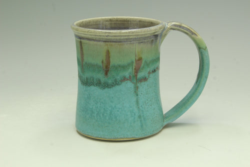 Turquoise ceramic mug with a handle on a light gray background