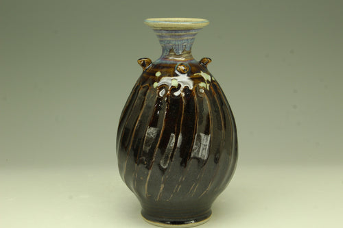Ceramic vase with brown glaze and decorative elements on a plain background