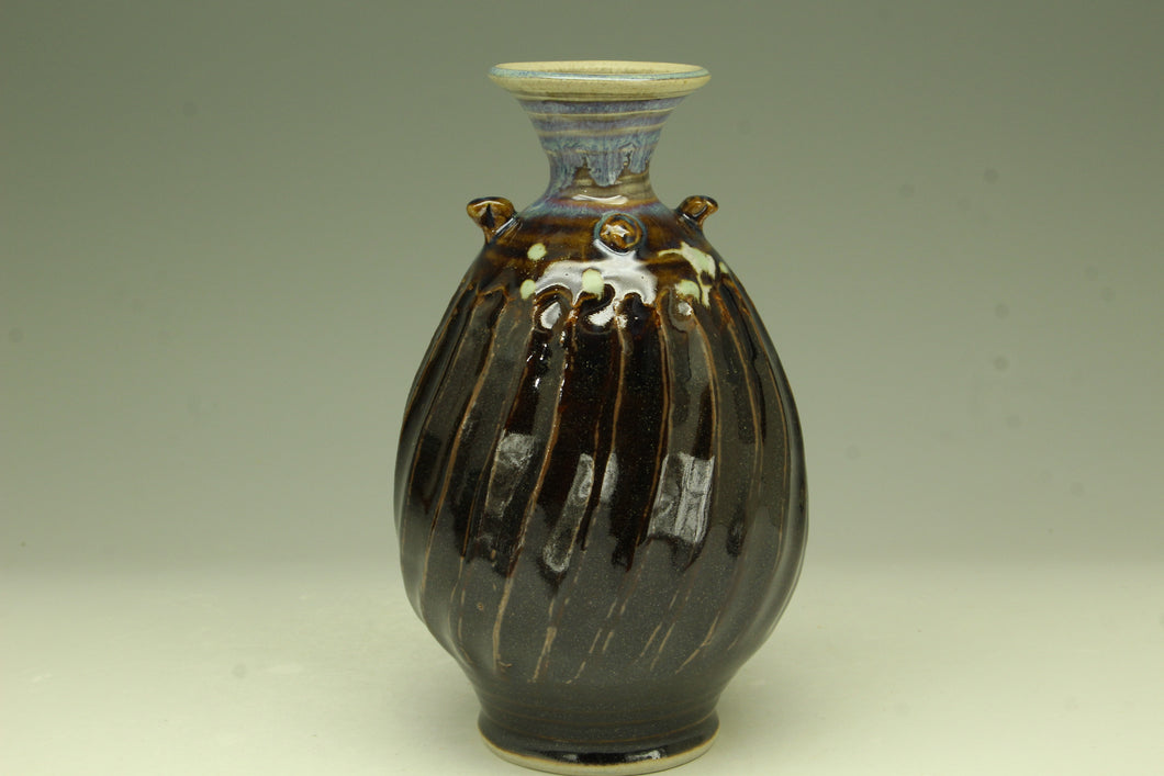 Ceramic vase with brown glaze and decorative elements on a plain background